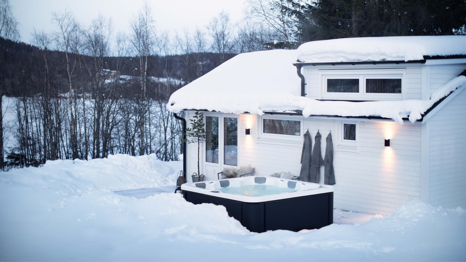 Vitt attefallshus i vintermiljö med en jacuzzi